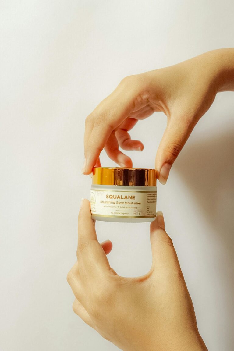 Hands holding a cosmetic jar of squalane moisturizer against a white background.
